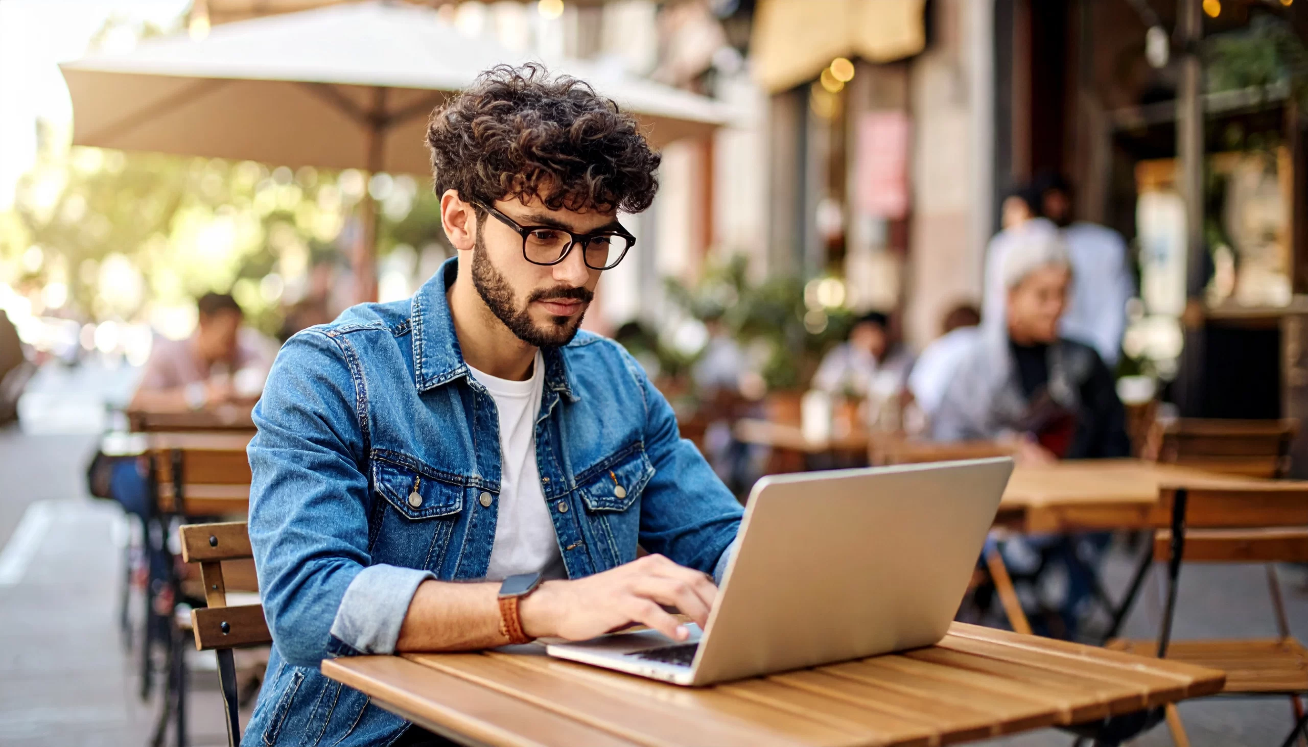 Estudiante universitario trabajando en una laptop en una terraza, representando el acompañamiento profesional y la organización paso a paso para realizar una tesis universitaria con éxito.